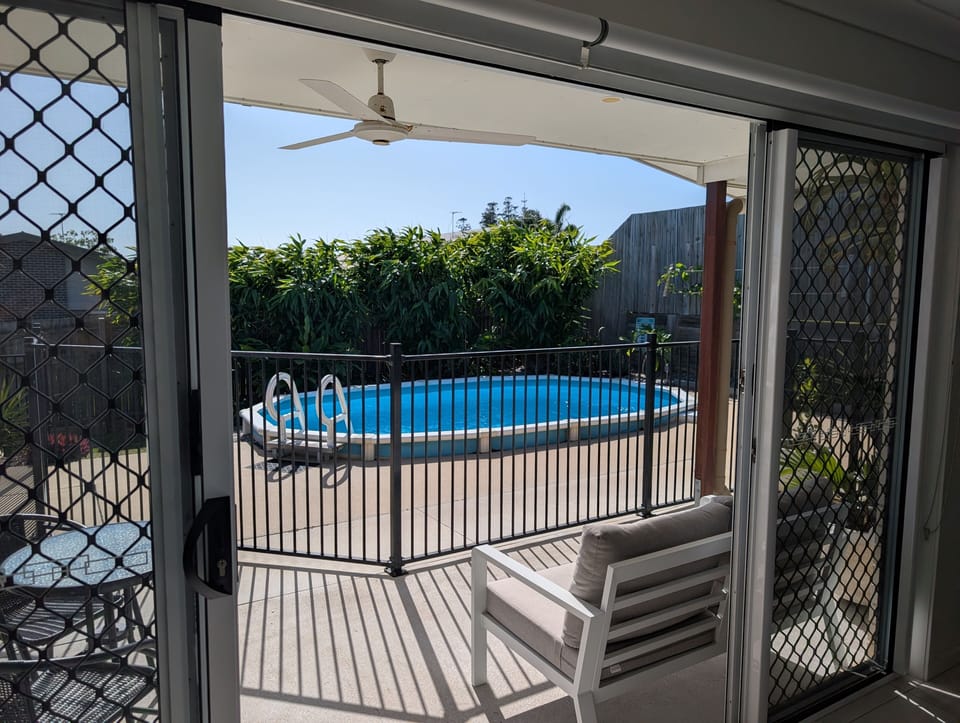 Covered patio with ceiling fan and fenced private pool oasis