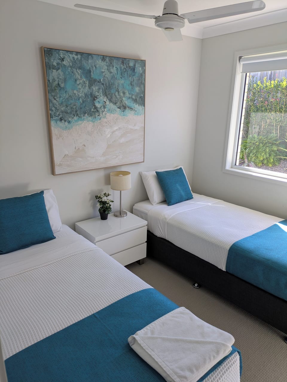Bright twin room with coastal styling, natural light, and crisp linens
