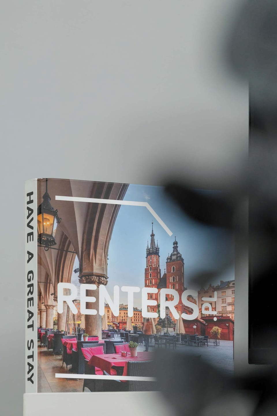 A decorative sign displayed on a glass surface near the apartment entrance. Reflections and modern surroundings create a stylish urban atmosphere.