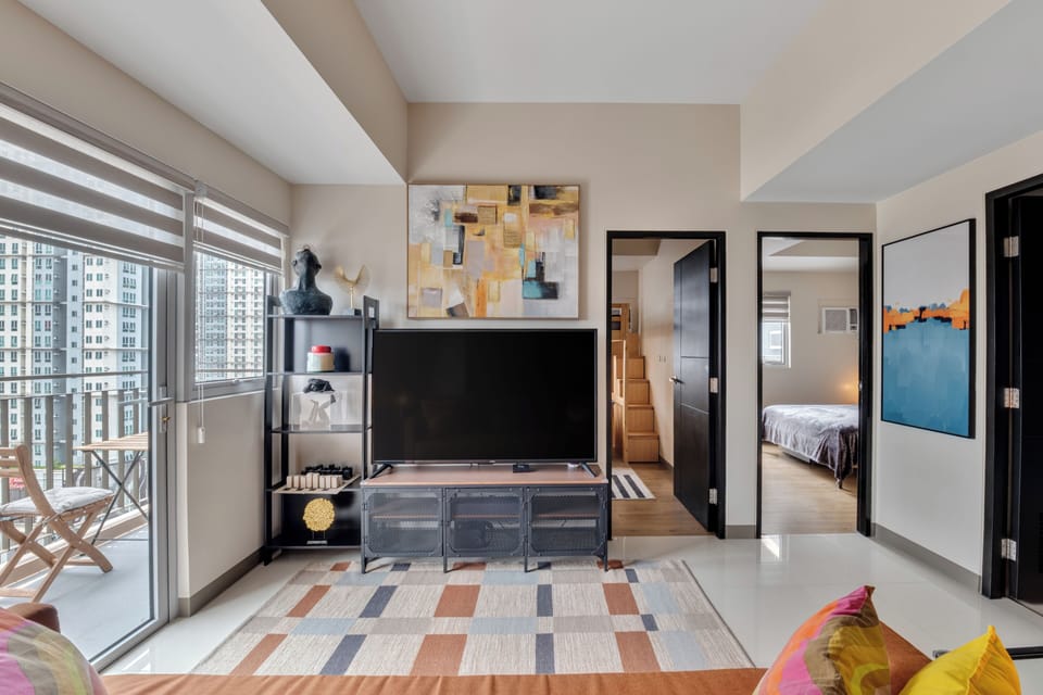 Bright city-view lounge with large windows, smart TV, and modern decor