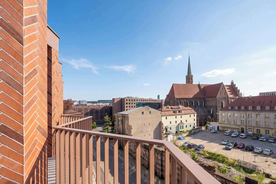 A balcony perspective overlooking rooftops and city buildings. The elevated view highlights the vibrant urban environment.