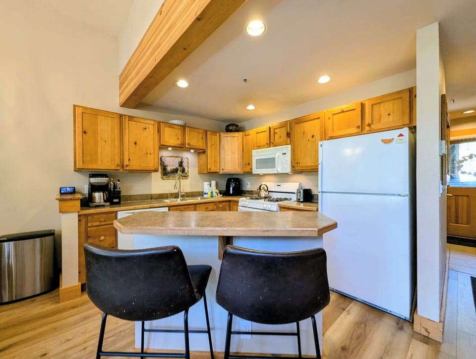 Your fully equipped kitchen features warm wood cabinetry, modern appliances, and a cozy breakfast bar where you can sip morning coffee and plan the day's adventures.