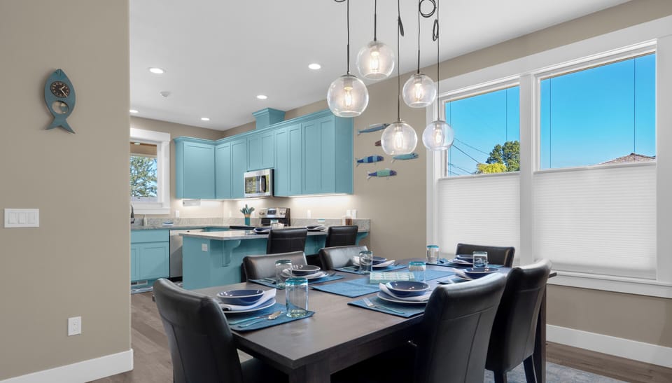 Gather around your stylish dining table beneath stunning pendant lights, with turquoise kitchen cabinets creating a coastal vibe for memorable meals.