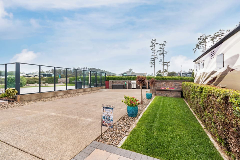 An inviting outdoor property area with lush green lawn, paved pathways, colorful planters, and scenic surroundings perfect for relaxation.
