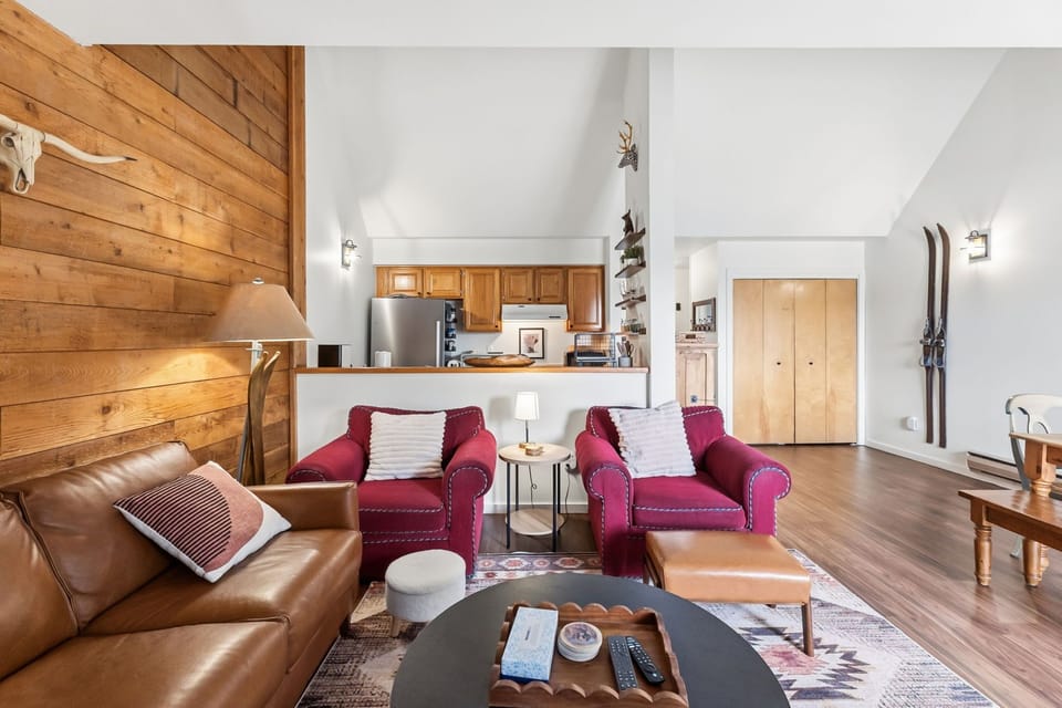Cozy up in your alpine-inspired living room with warm wood accents, leather seating, and mountain memories displayed on the walls.