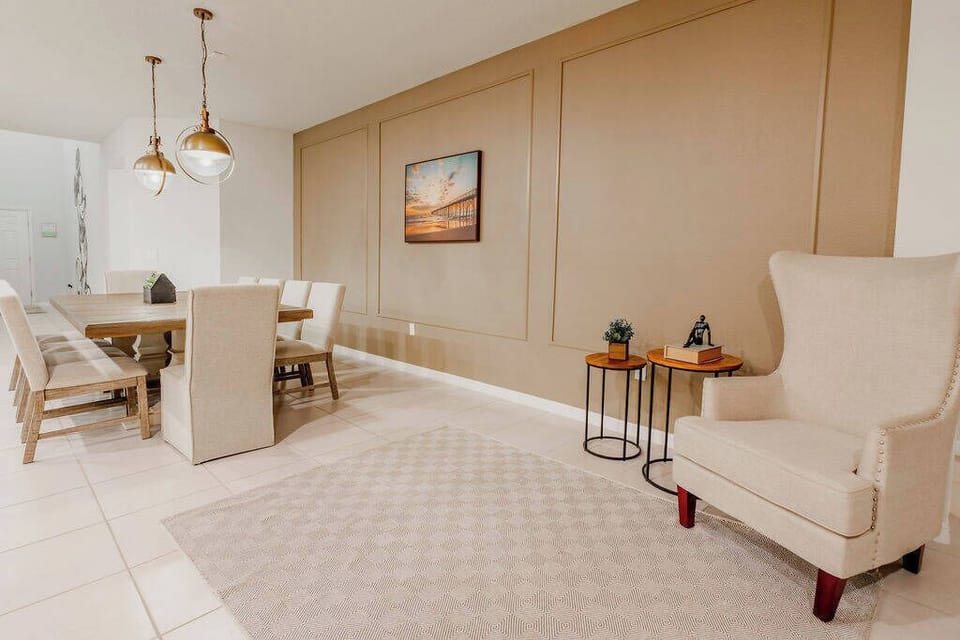 Enjoy the charm of this stylish dining area with a warm wood table, comfortable chairs, and glowing pendant lights. The textured rug adds coziness, while subtle artwork creates an inviting atmosphere for your dining experience.