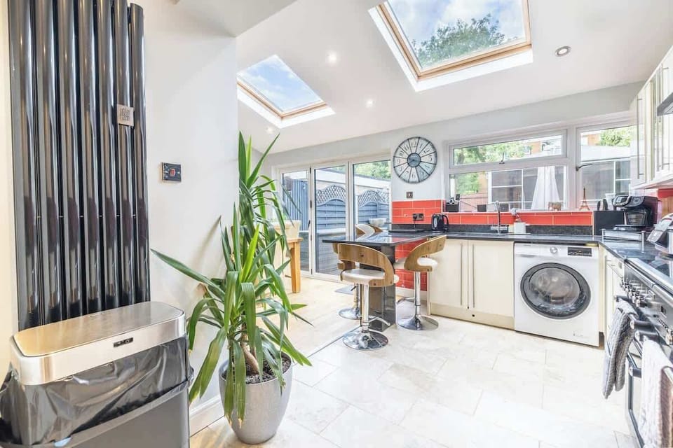 Modern kitchen with skylights, plants, and sleek white finishes throughout
