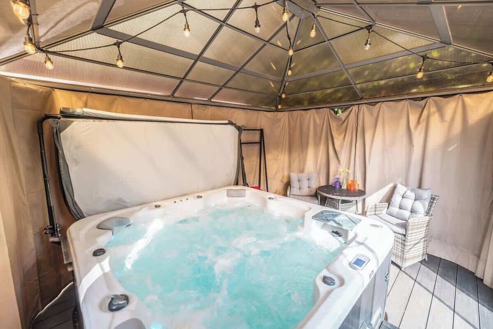 Relaxing hot tub under gazebo with soft lighting and privacy curtains
