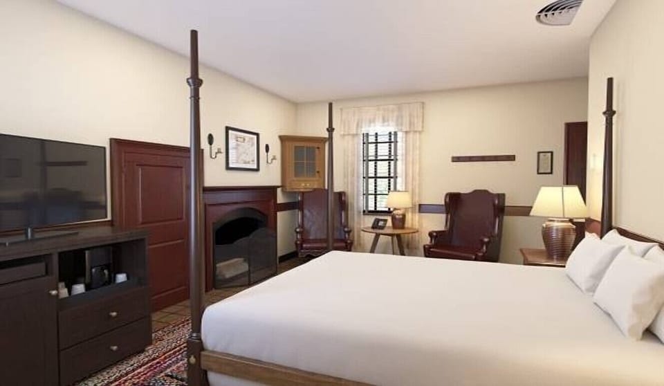 Recharge in a polished four-poster room with cozy seating.