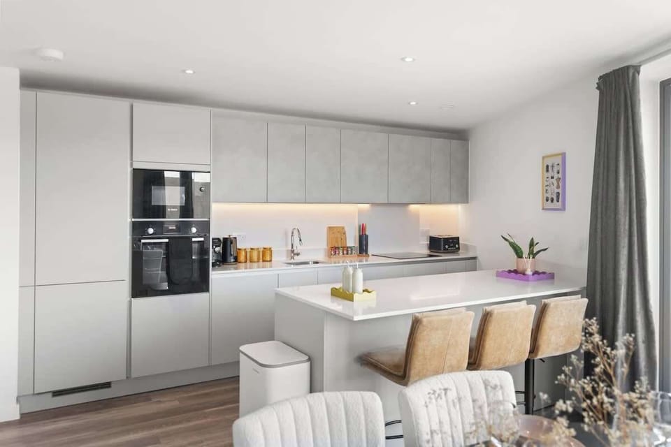 Modern kitchen w/ sleek cabinets, built-in appliances & island seating