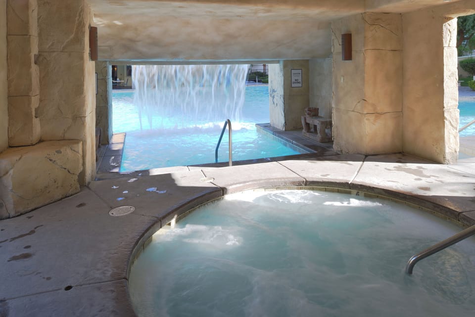 Unwind in bubbling spa beside a serene waterfall pool.