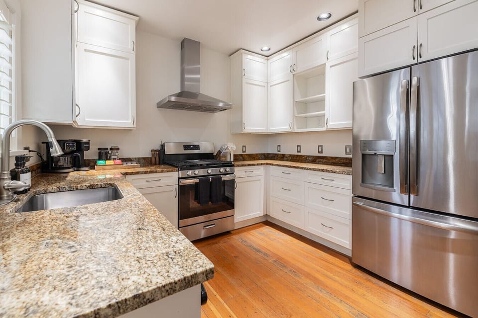 Chef-ready kitchen with granite island, range hood, and warm hardwood floors