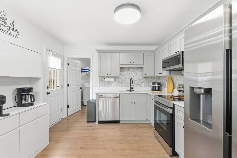 This bright, fully stocked kitchen opens directly to a private laundry area and shaded backdoor entry—perfect for quick access to the outdoors. The sleek layout and stainless steel appliances offer both function and flow for day-to-day living.