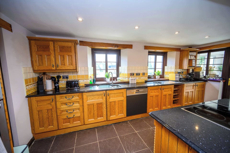 Fully equipped for modern entertaining, including a cooker and hob, generous preparation space, a large fridge-freezer, coffee machines, and extensive cookware.