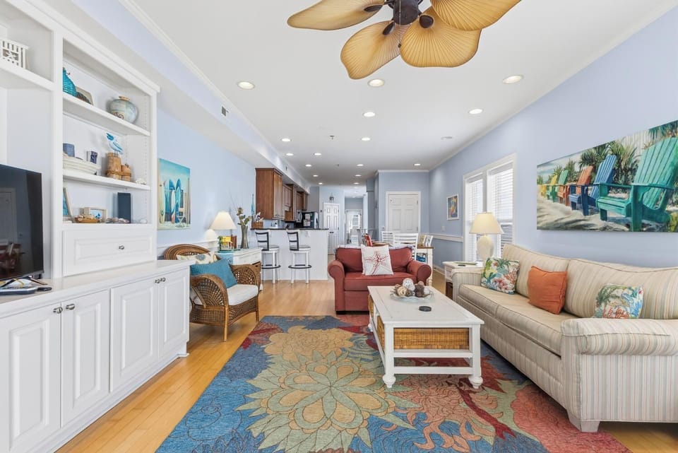 Relax in your bright coastal living space, where beach-themed decor and comfortable seating invite you to unwind. The open layout connects seamlessly to a fully-equipped kitchen, perfect for your vacation getaway.
