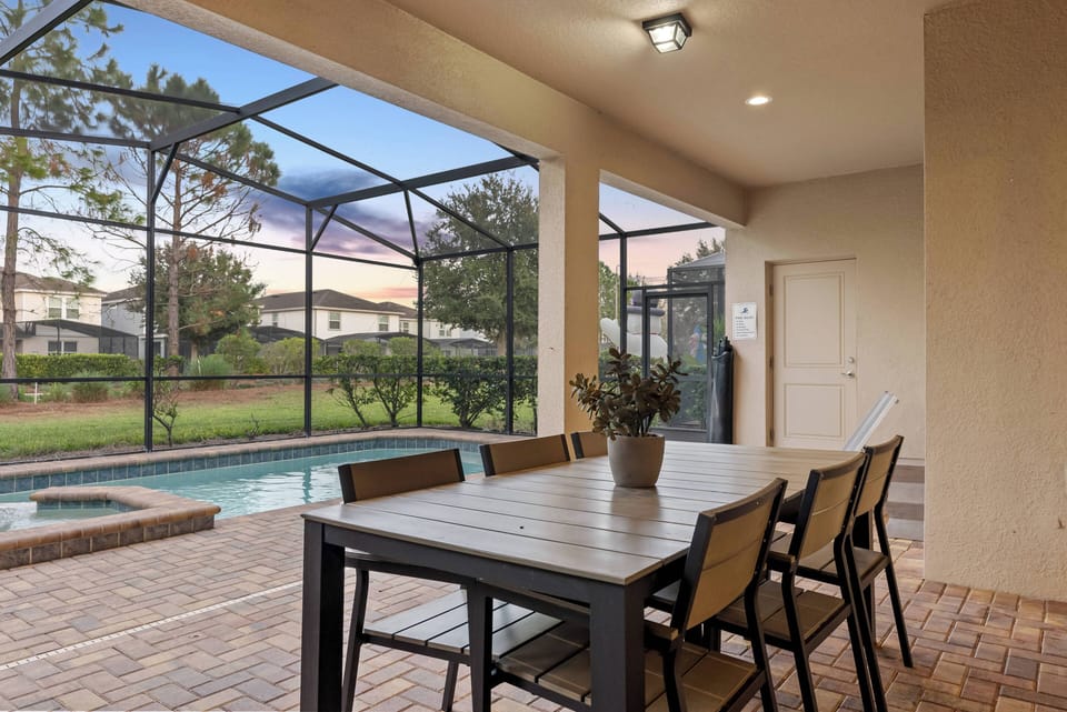Step outside to a charming covered patio with a stylish wooden dining table, perfect for al fresco meals. Enjoy serene pool views surrounded by lush greenery, and spend relaxing evenings watching sunsets in comfort.
