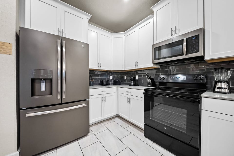 Experience a stylish kitchen featuring sleek black appliances and bright white cabinetry. With modern tile flooring and ample counter space, meal prep is effortless in this inviting setting that makes cooking a joy!
