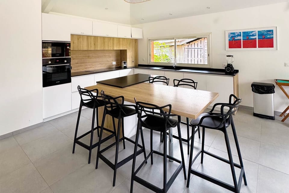Open-plan kitchen, island with bar stools, modern fittings, colourful canvas above:<br>The large open-plan kitchen is one of this villa's standout features — sleek, fully equipped, and designed for groups who love to cook and gather together.