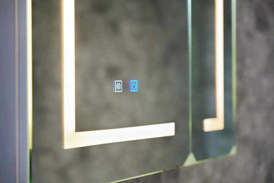 A standout feature of the apartment, this bathroom includes a large jacuzzi tub with side controls, dual shower heads, a sleek light-up mirror, and heated towel rail, creating a relaxing and practical environment.