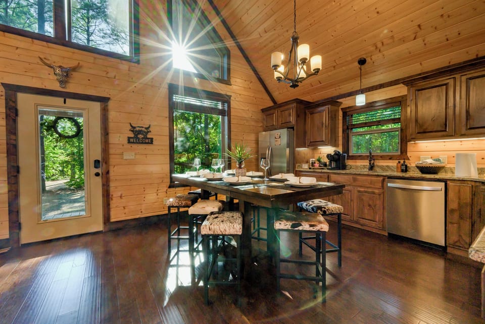 Sunlit rustic kitchen with island seating and beautiful forest views