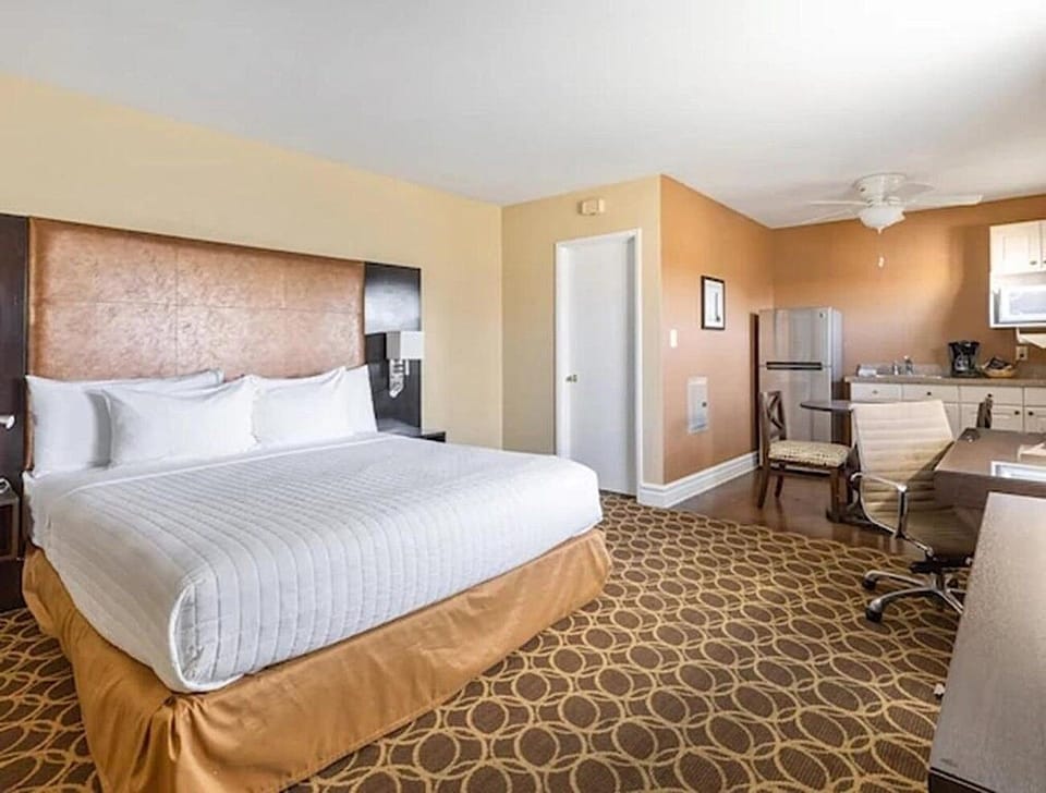 Unwind on crisp linens with workspace and kitchenette nearby.