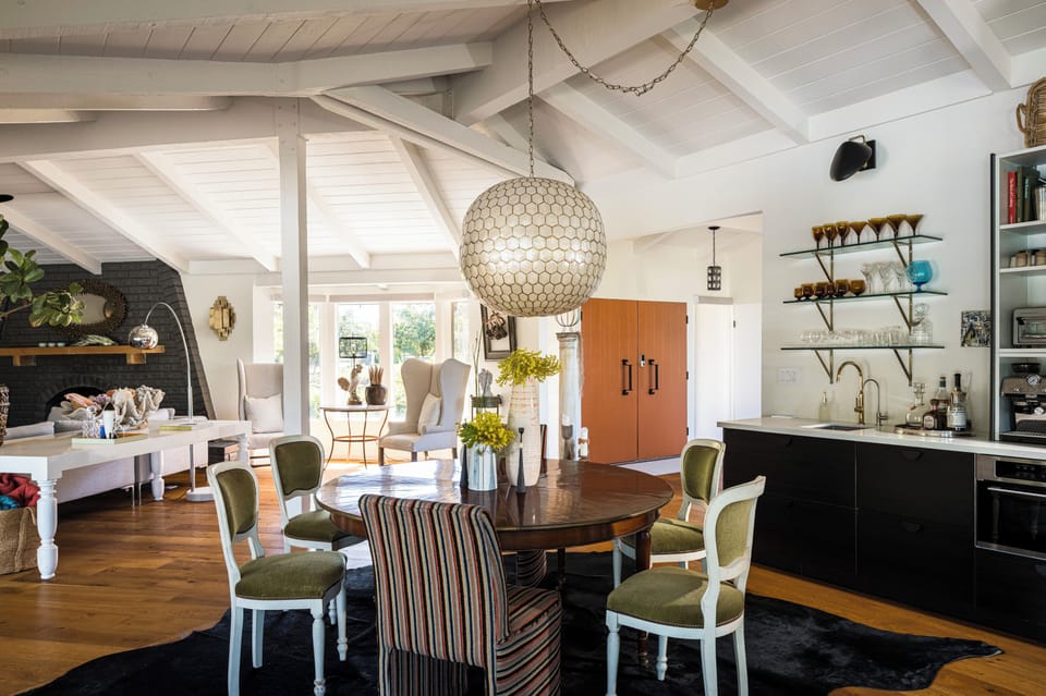Gather around the elegant round table in this sun-drenched open space, where vaulted ceilings and charming vintage touches create an inviting backdrop for memorable meals with loved ones.