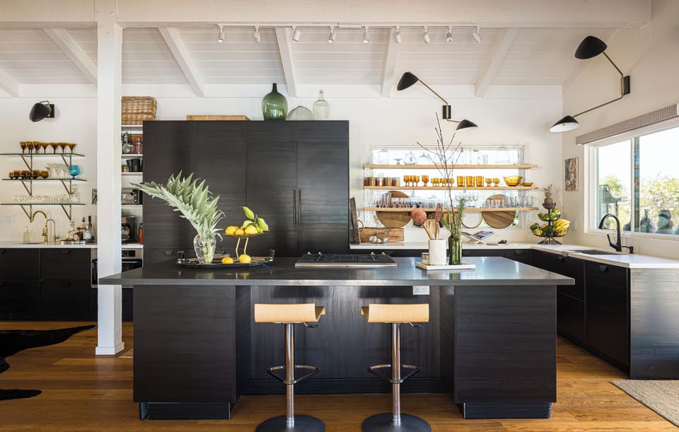Gather in this stunning chef's kitchen with sleek black cabinetry, a spacious island perfect for morning coffee, and open shelving stocked for your culinary adventures.