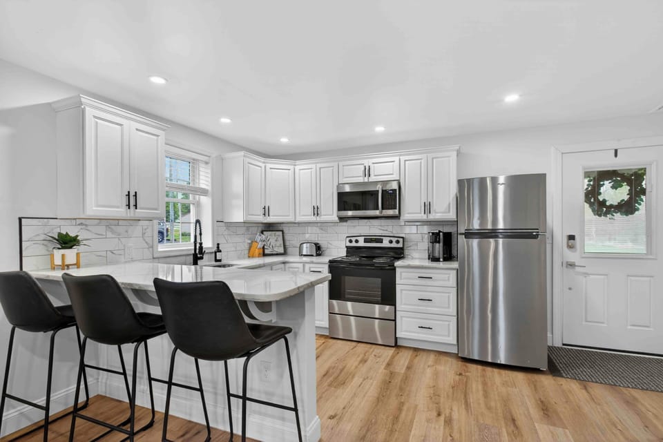 Bright chef’s kitchen with quartz bar, seating for three, stainless steel appliances