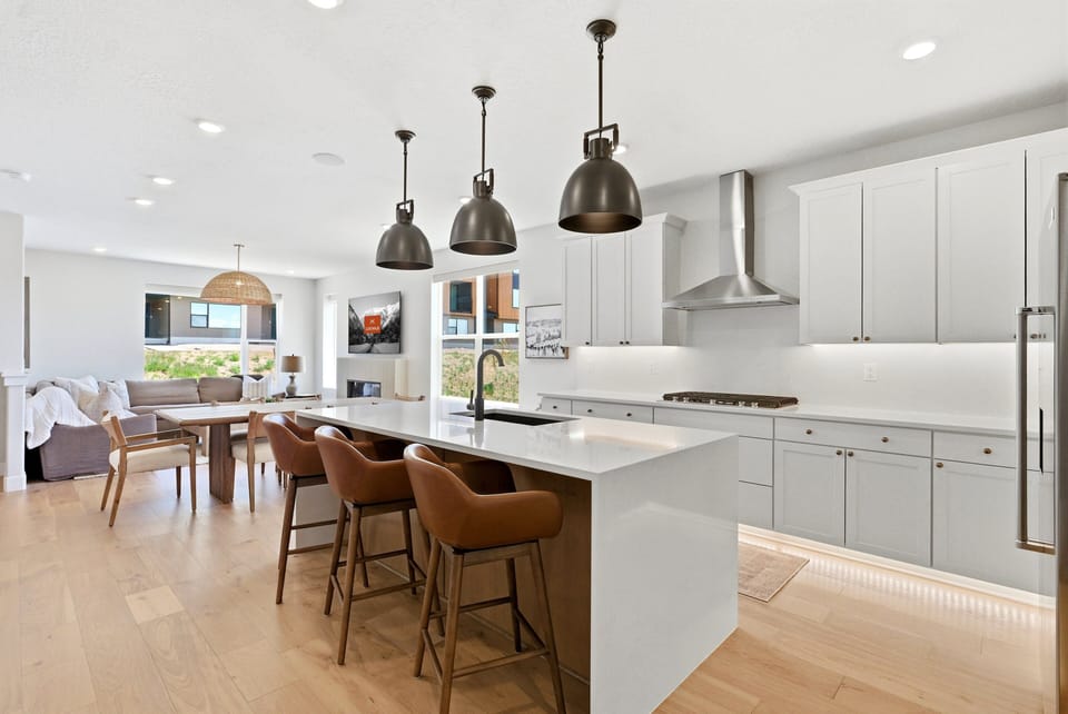 Gourmet kitchen with white cabinetry, oversized island, bar seating, and open flow into the dining area.