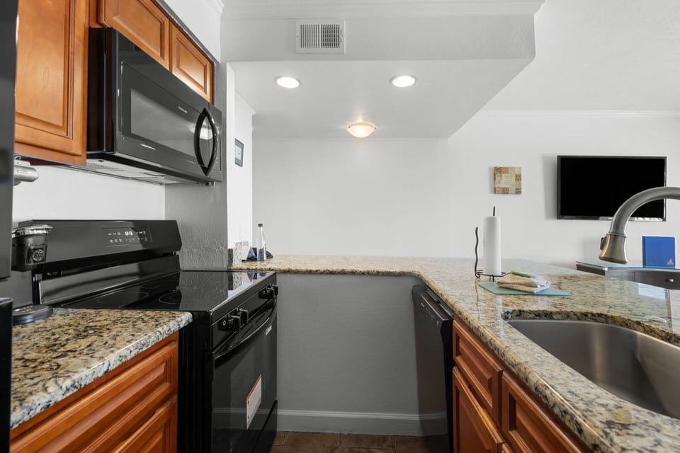 Cook up delicious meals in this modern kitchen, complete with sleek black appliances and granite countertops.
