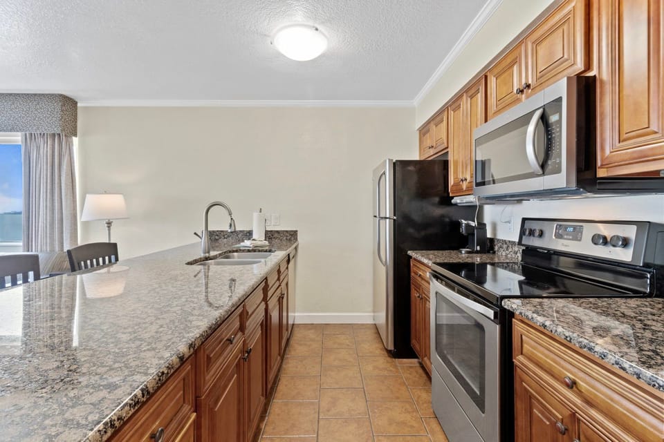 Cook up your favorite meals in this modern kitchen, surrounded by rich wood cabinetry and sleek appliances.