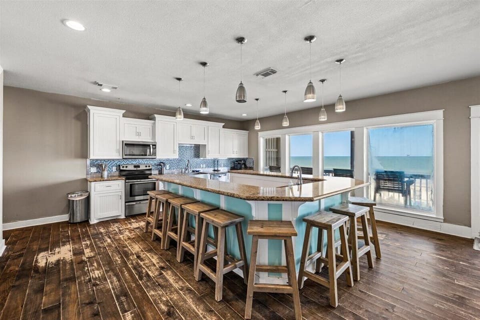 Bright beachfront dining and kitchen area with modern pendant lighting and expansive Gulf Coast views.