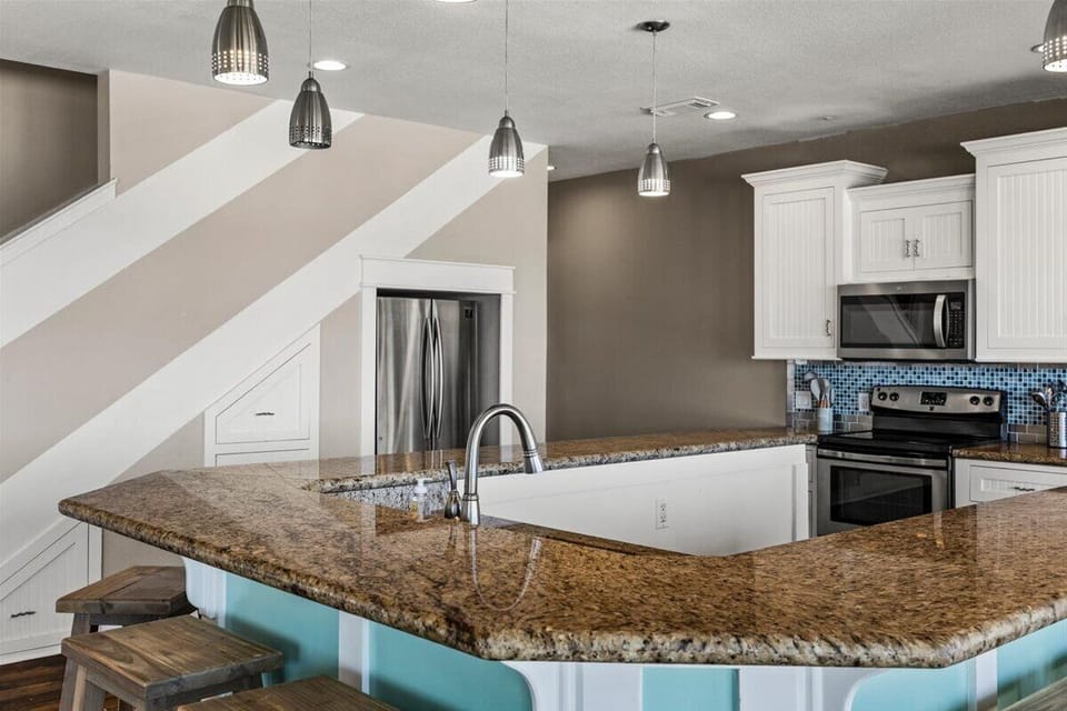 Fully equipped coastal kitchen with stainless steel appliances, granite countertops, and spacious prep areas for vacation cooking.