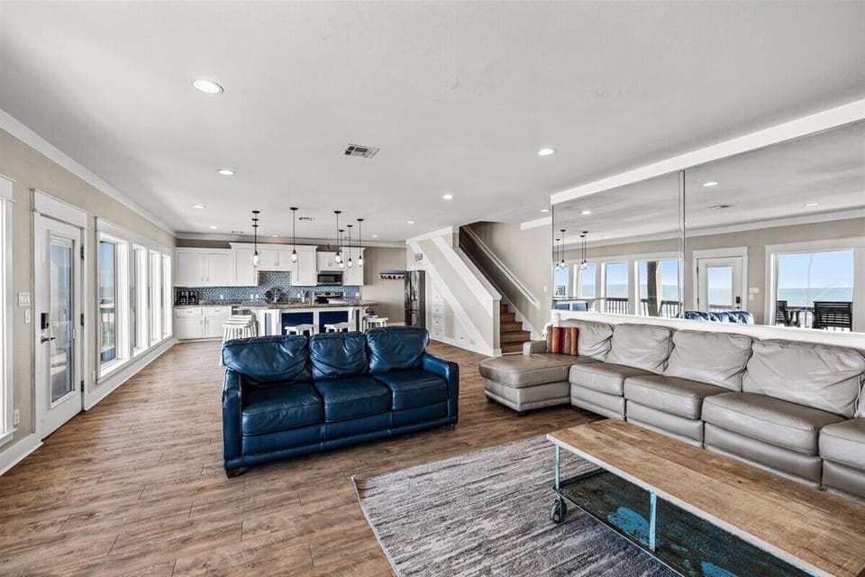 Modern open floor plan with spacious living room, coastal furnishings and direct views into the gourmet kitchen and dining areas.