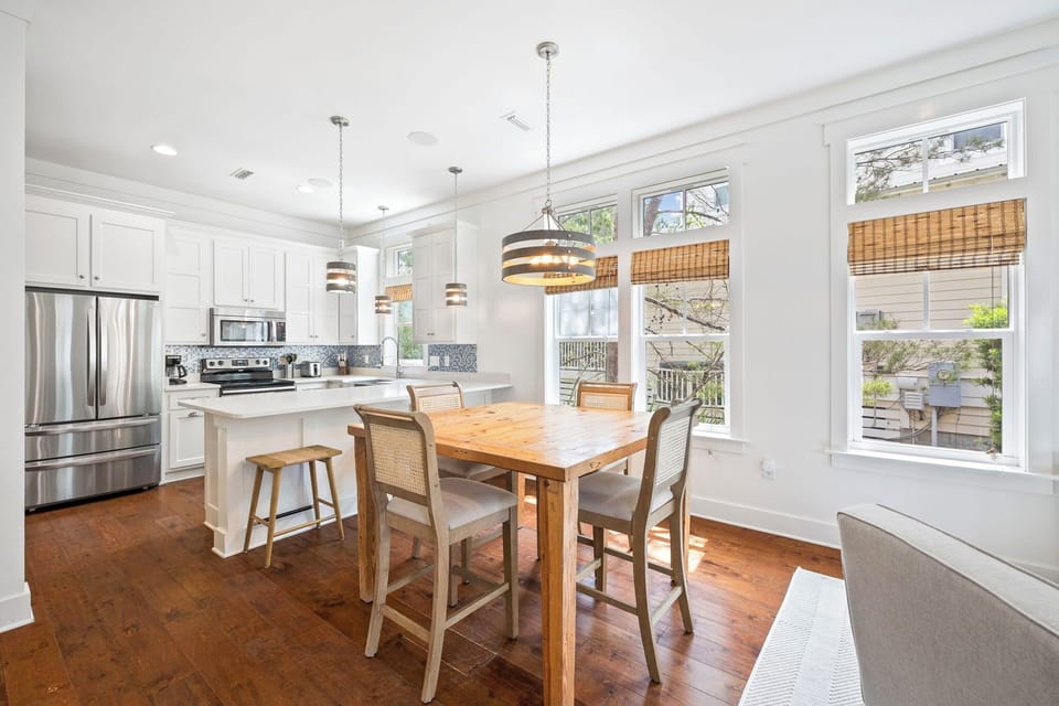 Gather around the warm wood table where sunlight streams through bamboo shades, creating the perfect spot for your morning coffee or shared meals with loved ones.