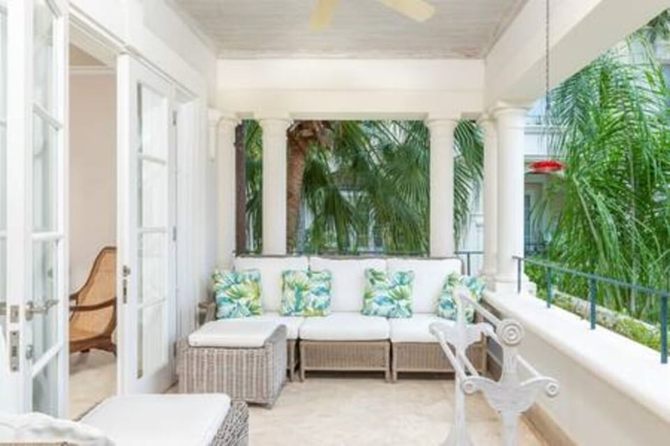 Private balcony area with outdoor seating and views to the communal pool area and sea beyond.