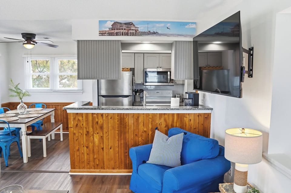 Bright coastal kitchen with breakfast bar, stainless suite & big TV