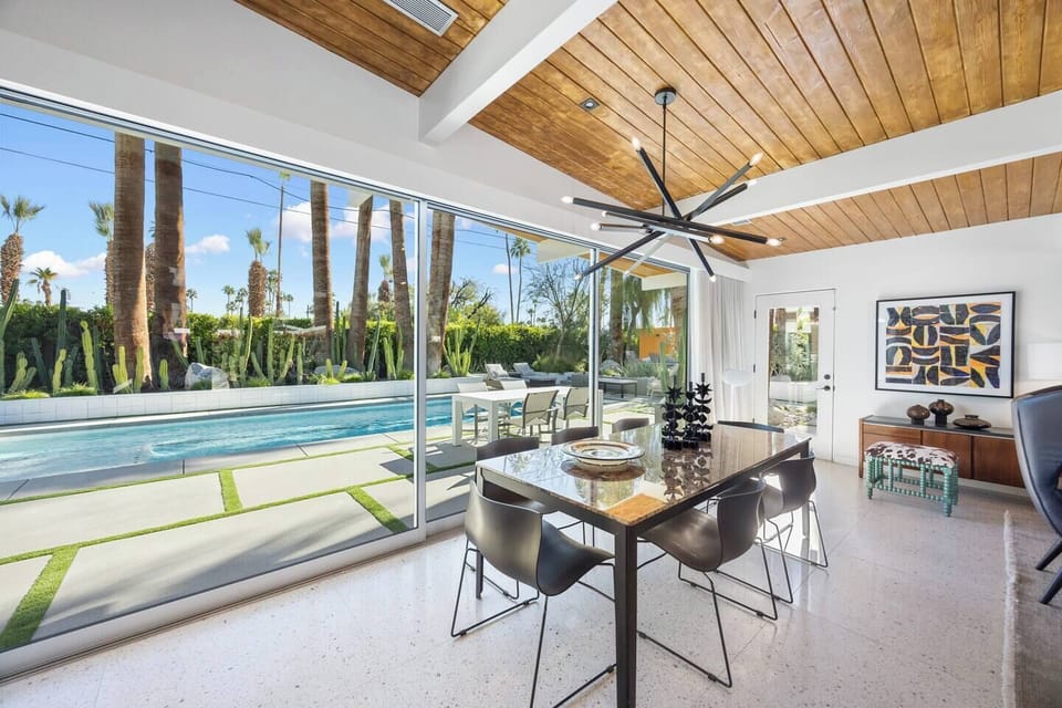 Formal dining room with designer lighting and floor-to-ceiling glass sliders opening directly onto the pool terrace.