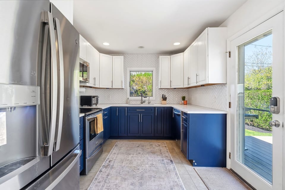 Renovated kitchen with navy cabinets, quartz counters, and herringbone tile