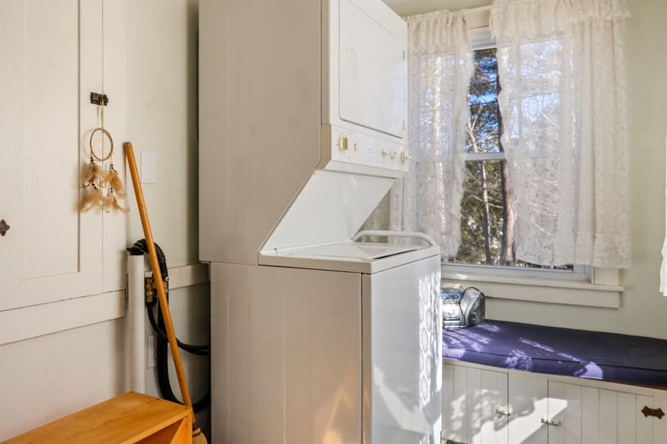 Our entry nook offers a stacked washer and dryer for refreshing gear mid-stay. This functional space includes a built-in bench and shoe rack, perfect for transitioning from the trails of Acadia to the comfort of your 1870s Somesville retreat.