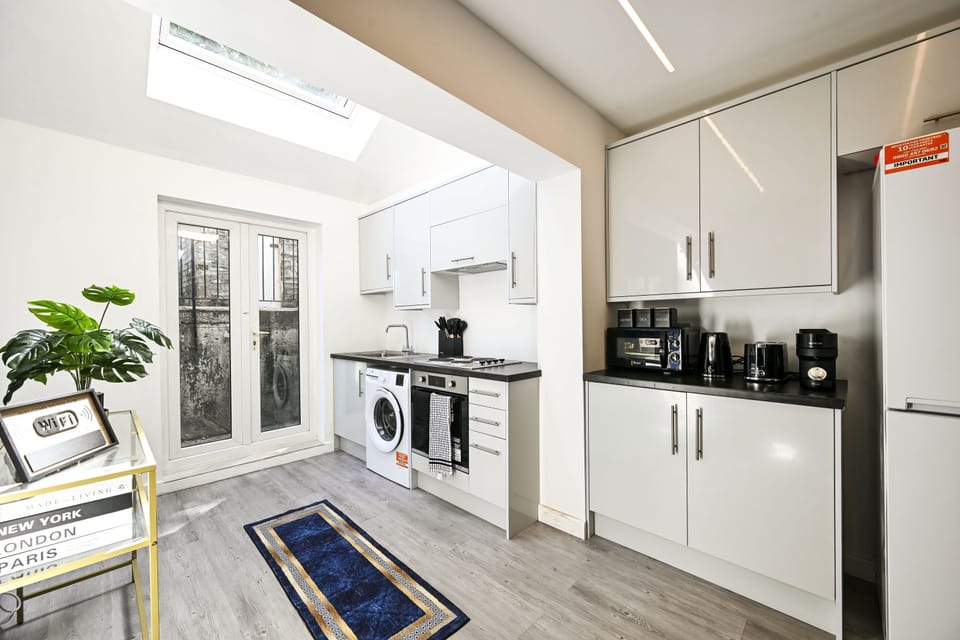 Kitchen under the skylight, with the washing machine, oven and hob and glazed doors at the end