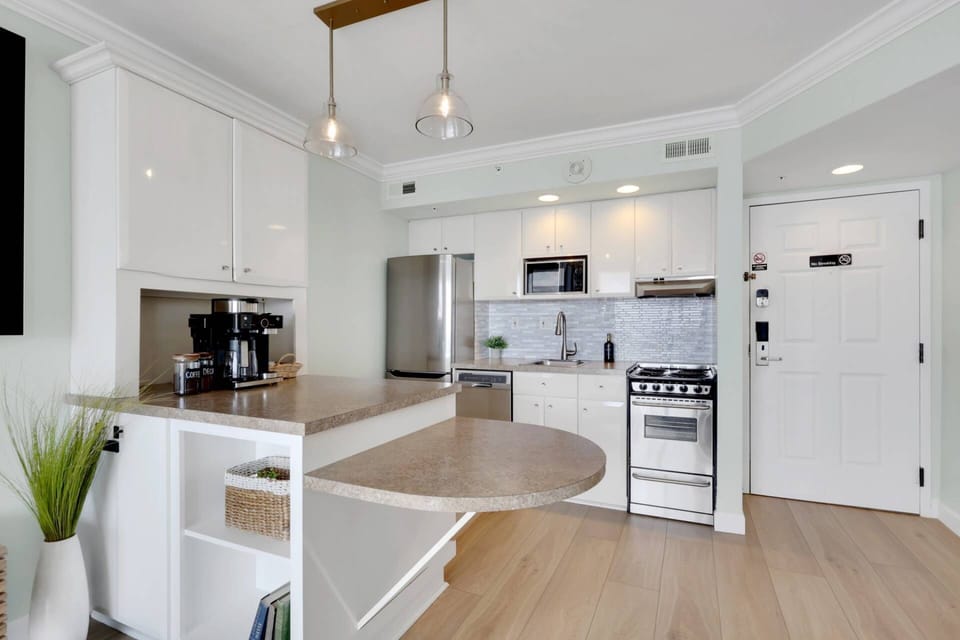 Sleek finishes, stainless steel appliances, and an open layout keep the kitchen connected to the relaxed waterfront feel of the condo