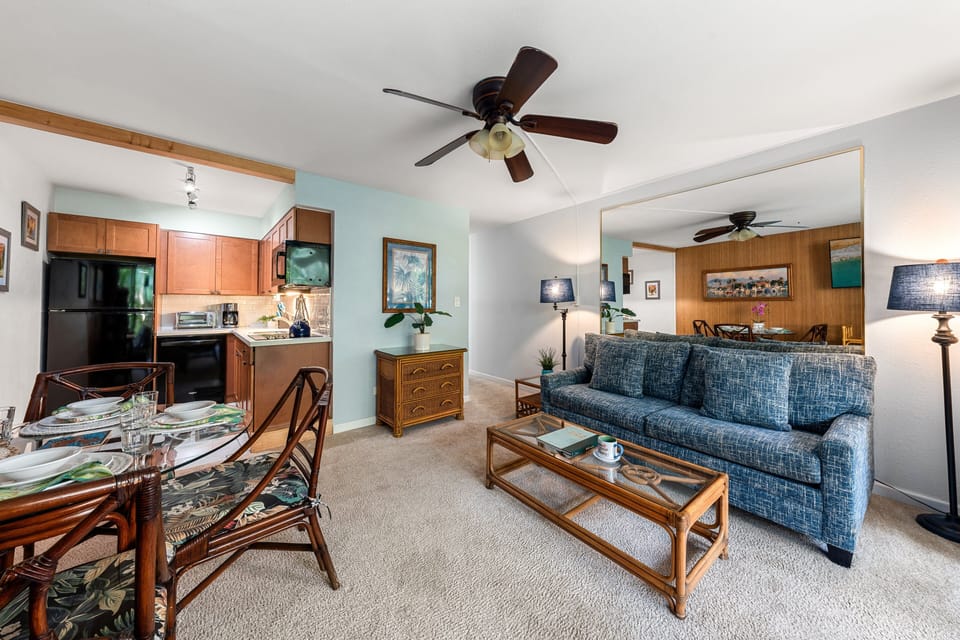 Blue sofas and wood paneling glow in natural light, coastal paintings carrying the theme indoors.