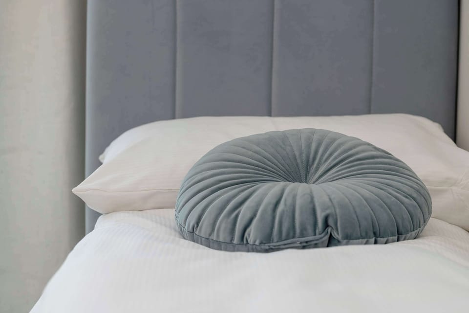 A decorative bedroom detail with soft pillows and upholstered headboard.