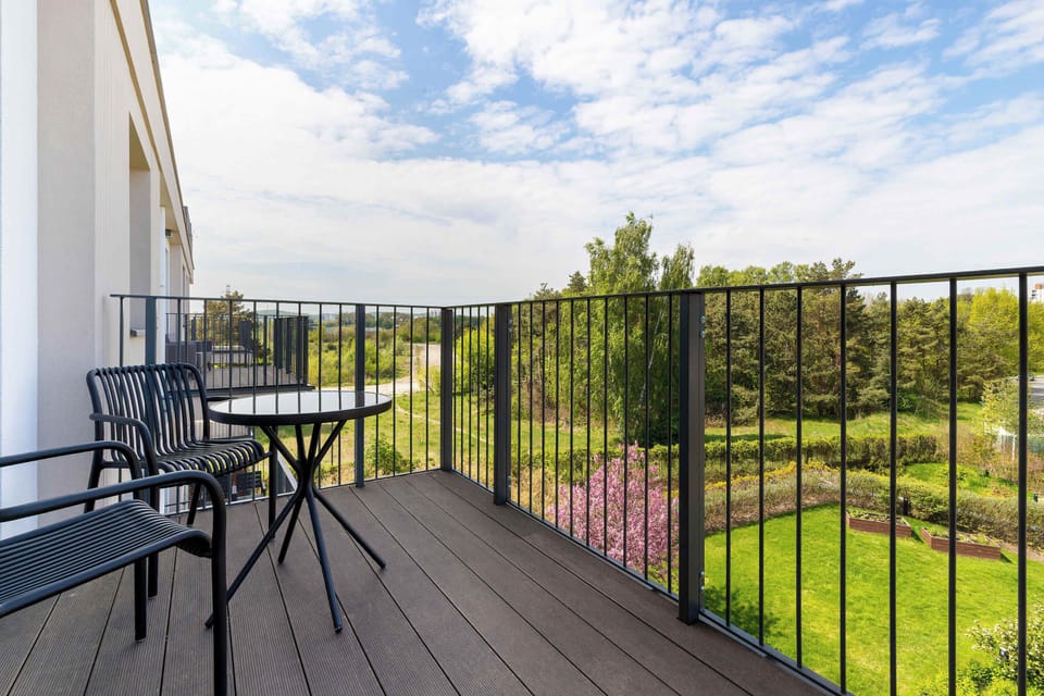 A spacious balcony with outdoor seating and a peaceful green view.
