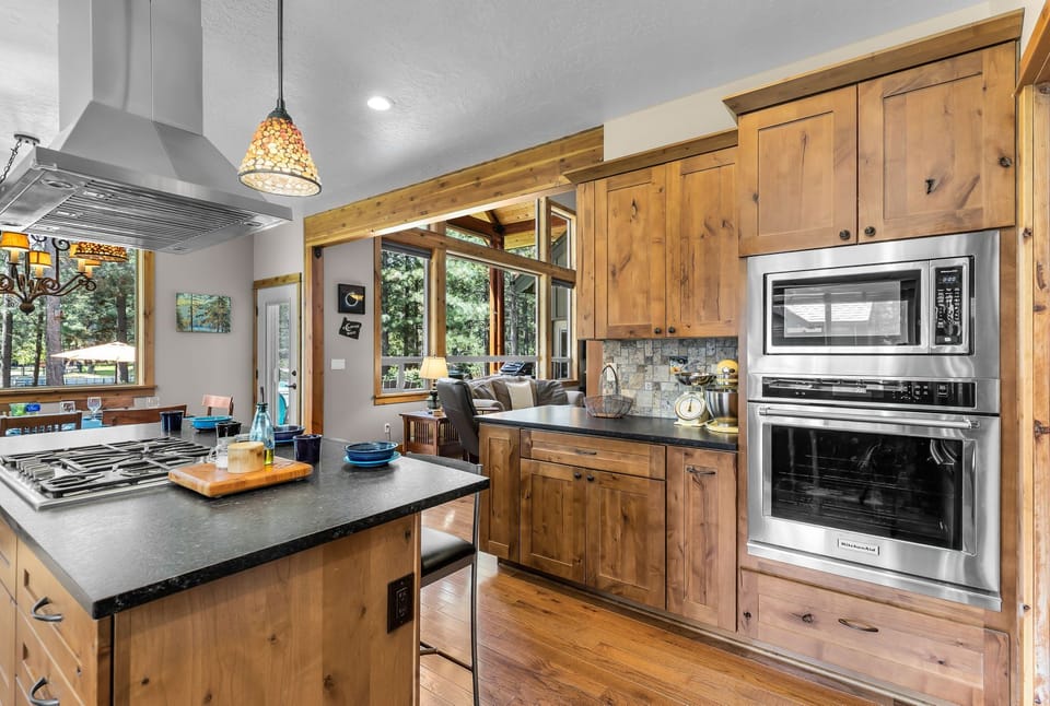Picture yourself cooking in this inviting kitchen, where warm knotty pine cabinets and sleek appliances meet. Natural light pours in, connecting you to the living spaces and forest views beyond.