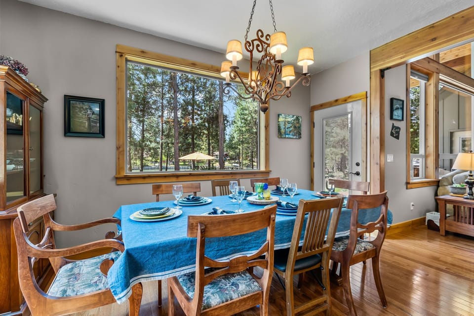 Gather around this warm dining space, where natural light pours in through windows framing peaceful forest views. You'll love sharing meals under the elegant chandelier.