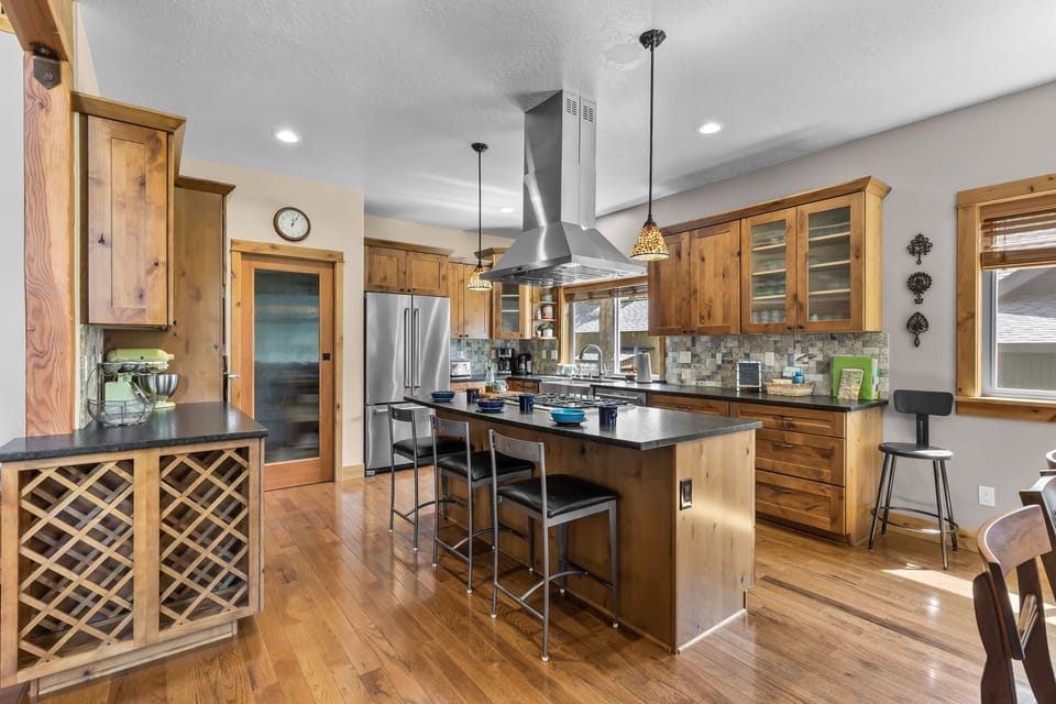 A spacious chef's kitchen with warm wood cabinetry, granite countertops, and a large island where you'll gather with friends over coffee and conversation. Stainless steel appliances and thoughtful pendant lighting complete this inviting culinary space.