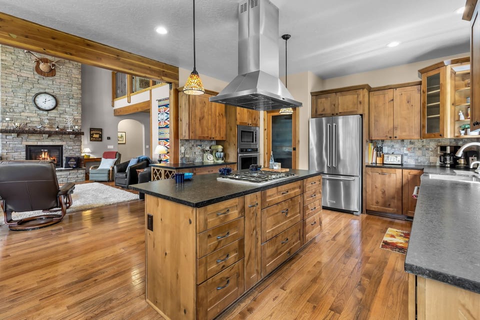 Your spacious chef's kitchen features rich wood cabinetry, modern stainless appliances, and a large island—perfect for gathering, cooking, and creating memories in this warm open-plan retreat.