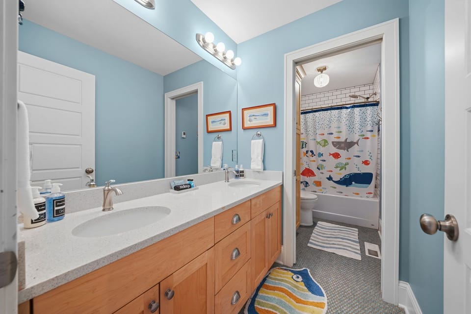 Your little ones will love getting ready in this cheerful bathroom featuring a whimsical ocean-themed shower curtain and bright, playful accents that make bath time an adventure.